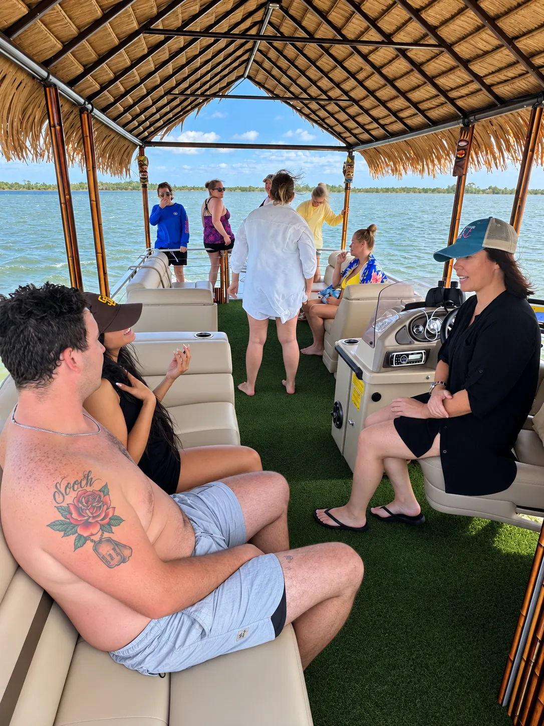 Guests on the tiki party boat deck with lounge seating and the captain console